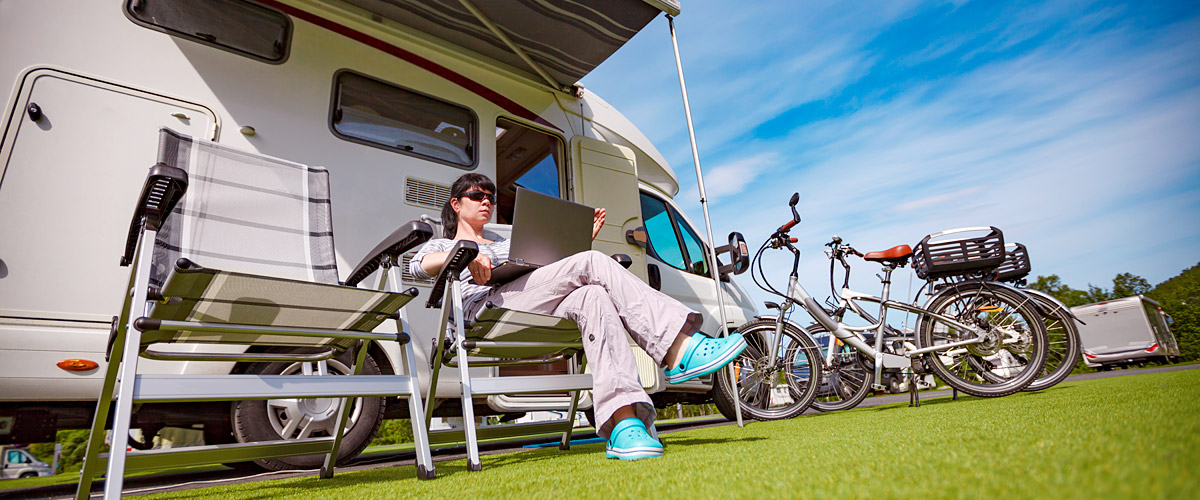 im Campingstuhl sitzender Besucher vor einem Wohnmobil, daneben 2 Fahrräder