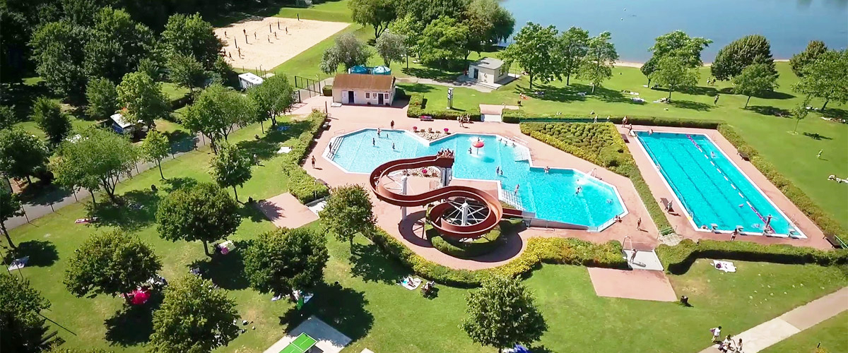 Swimming lake and outdoor pool complex features two stainless steel pools and slide, beach volleyball area, sunbathing lawn and part of the natural lake